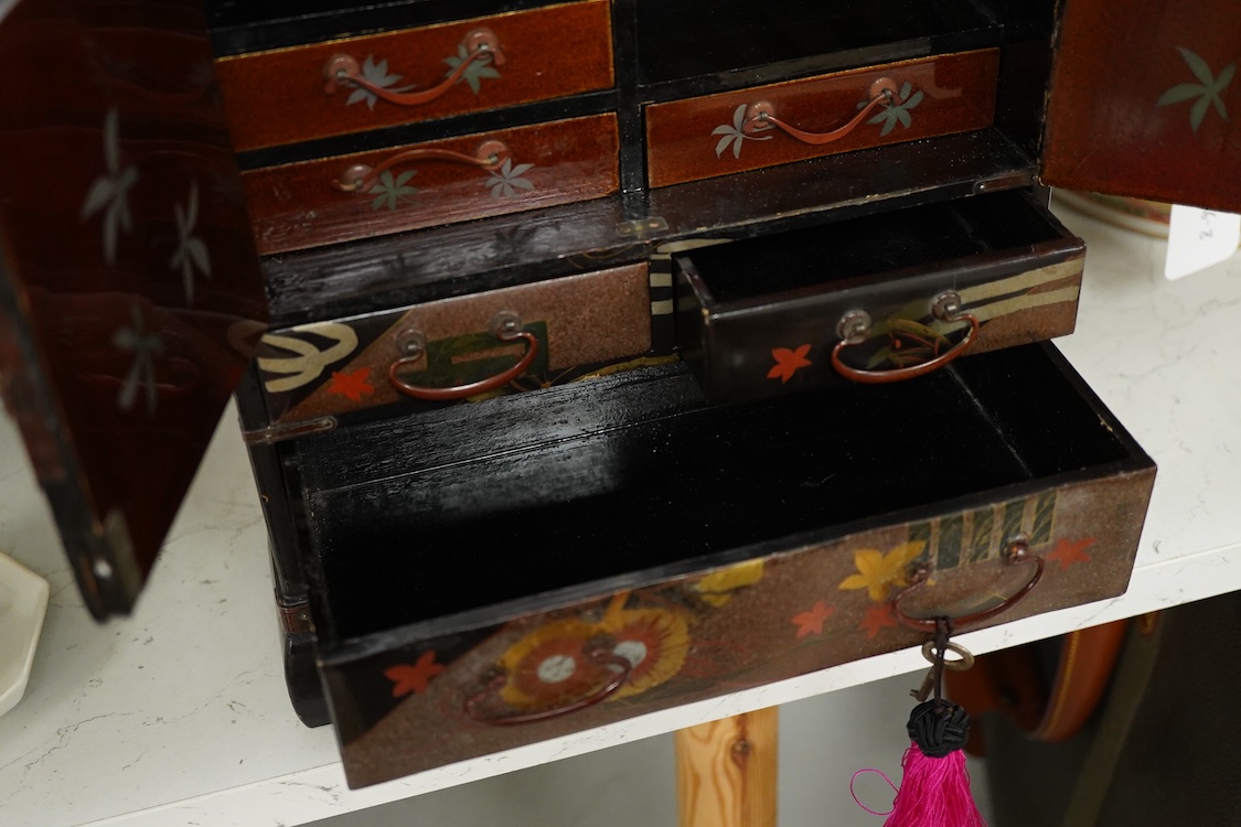 A Japanese gilt decorated black lacquer table cabinet, fitted with seven drawers, with key, 35cm high